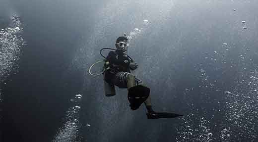 PADI Advanced open water diver hovers in the middle of water surrounded with bubbles