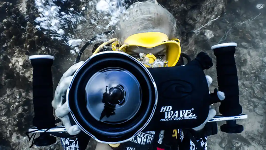 A reflection of an underwater videographer in the lens of an underwater camera