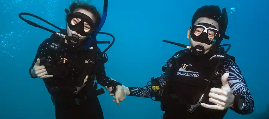 Dive buddies underwater holding hands