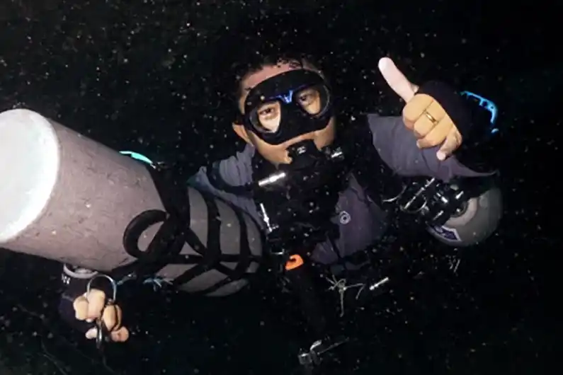 Diver on sidemount diving specialty course with one tank unclipped in front during swim through on Koh Tao