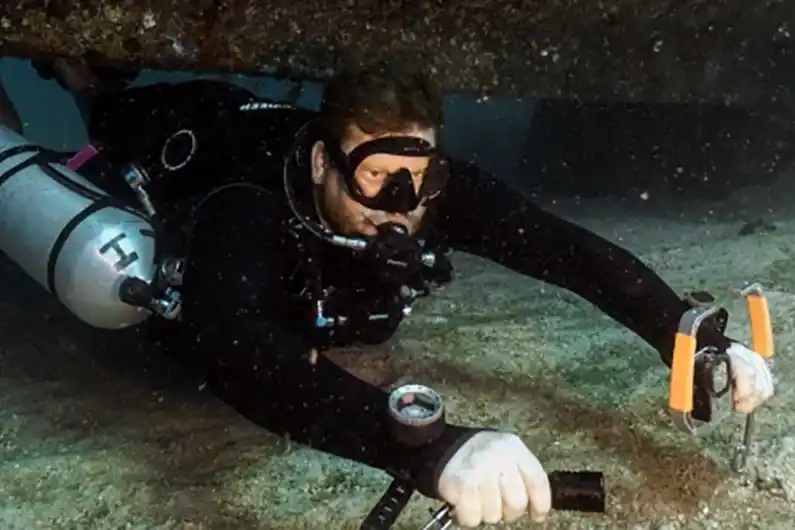Diver on sidemount diving specialty course swimming underneath HTMS Suphairin wreck Koh Tao