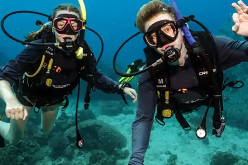 Two underwater navigation specialty course divers in the water happy